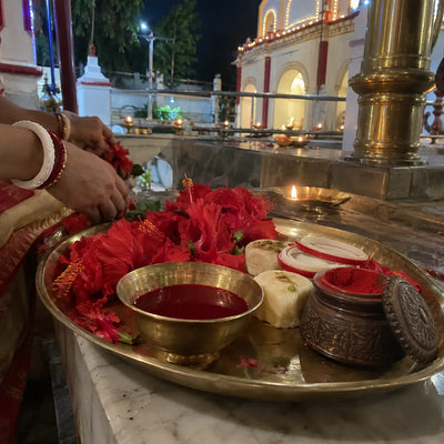 Alta, sindoor box, shankha-pola bangles and red hibiscus on a brass plate