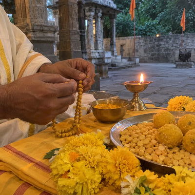 Turmeric mala, yellow marigolds, haldi and laddoos on a yellow cloth for Baglamukhi jaap