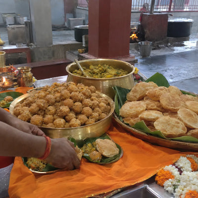 Brass vessels of laddoos and puri-sabzi prepared as bhog