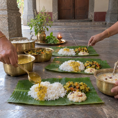 Rice, dal and kheer served on three banana-leaf plates from brass vessels