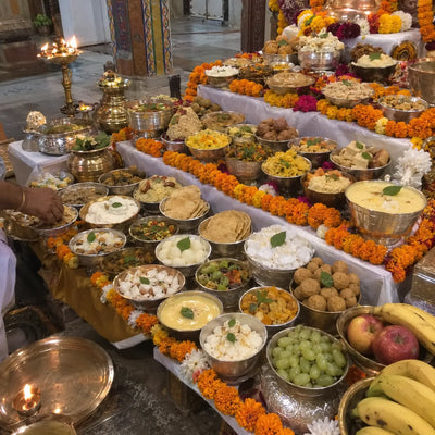 Chhappan bhog of 56 dishes in silver and brass bowls with tulsi
