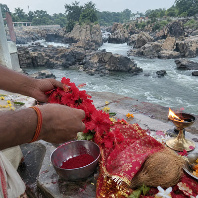 Red hibiscus garland and sindoor offered with a chunri and a diya