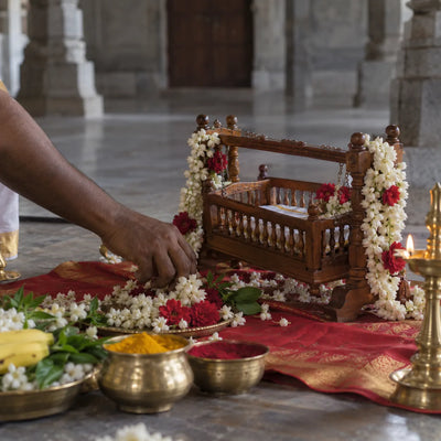 Garbarakshambigai Archana: a small flower-decked wooden cradle with jasmine and a lamp