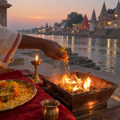 Yellow flowers and saffron rice offered into a small havan fire beside a brass lamp