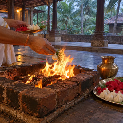 Durva grass and a modak offered into a havan fire with red hibiscus and a kalash