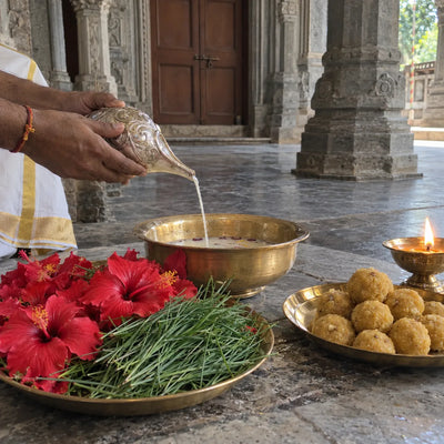 Panchamrit poured from a conch with hibiscus, durva grass and laddoos