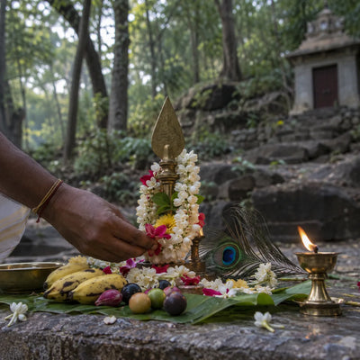 Murugan Archana: flowers, fruit and a peacock feather before a brass vel in a forest shrine