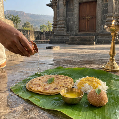 Puran poli, rice and varan on a banana leaf with a tulsi leaf and a samai lamp as naivedya