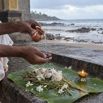 Sesame seeds and water offered onto kusha grass with rice pindas and white flowers by the sea