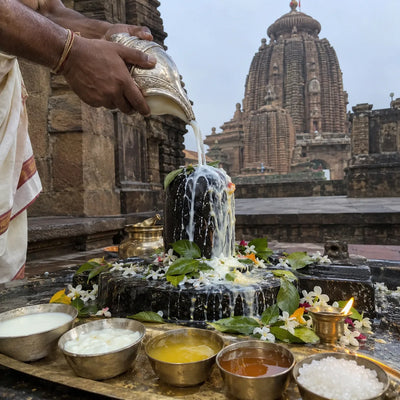 Panchamrit abhishek on a Shivling, Kalinga-style temple spire behind