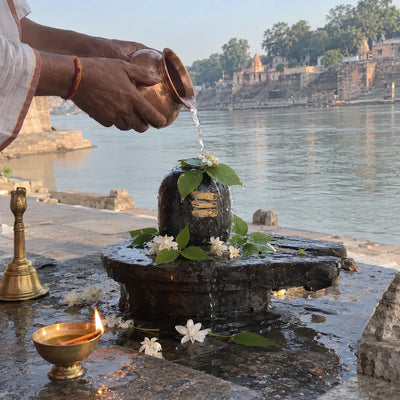 Water poured over a black stone Shivling with bilva leaves on a Narmada riverside ghat