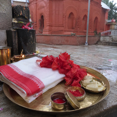 Red-bordered saree, hibiscus garland, alta and sindoor on a brass plate