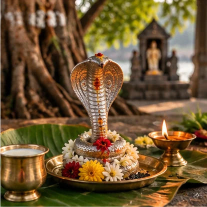 Silver naga pratima with flowers, milk and a diya for Sarpa Dosha puja