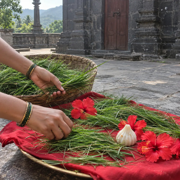Bundles of fresh durva grass offered on a red cloth with hibiscus and a modak