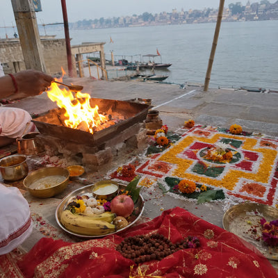 Havan fire beside a coloured vastu mandala with a mala and a chunri
