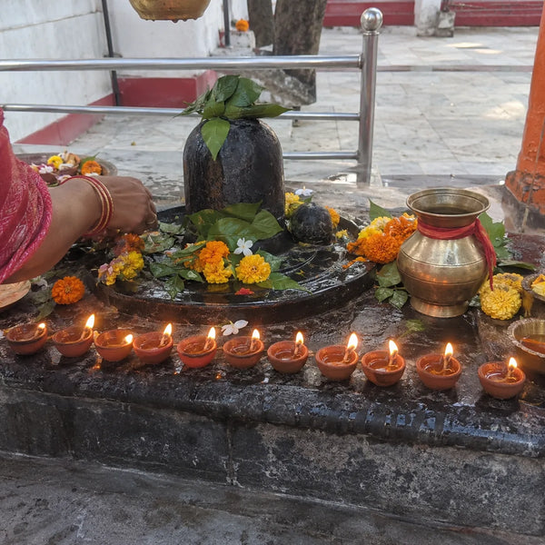 Eleven clay diyas lit before a Shivling for an 11-day sankalp