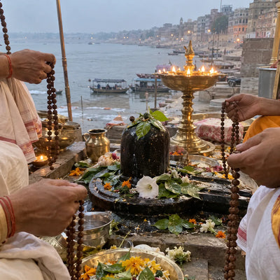 Rudraksha malas around a Shivling with a ghee lamp, Kashi ghats behind