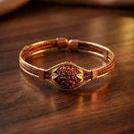 Bracelet with gold clasp and brown leather strap on a wooden surface