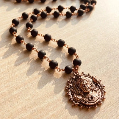 Karungali Malai (Copper Wire) with Lord Murugan Face Pendant on a wooden surface