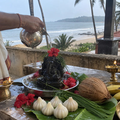 Abhishek kalash with modaks, durva grass and hibiscus, Konkan coast behind