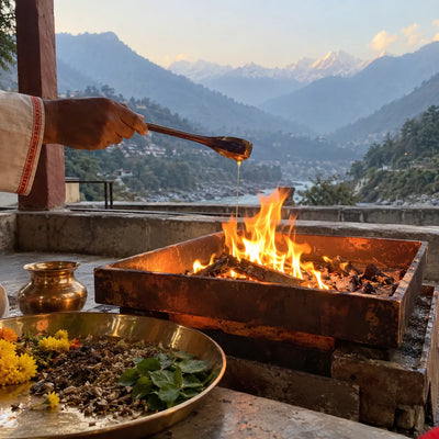Ghee poured into a havan fire with samagri and tulsi, misty Himalayan mountains behind