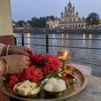 Red hibiscus garland and Bengali sweets offered with a brass lamp