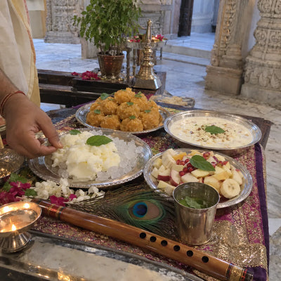 Silver plates of makhan-misri, laddoos and rabri with tulsi leaves