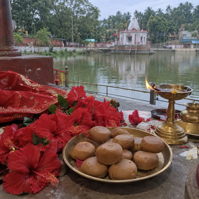 Brown pedas and a red hibiscus garland with a brass lamp