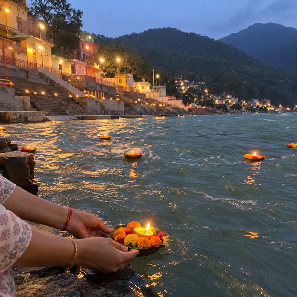 Hands releasing a leaf boat with a diya onto the Ganga at the evening aarti