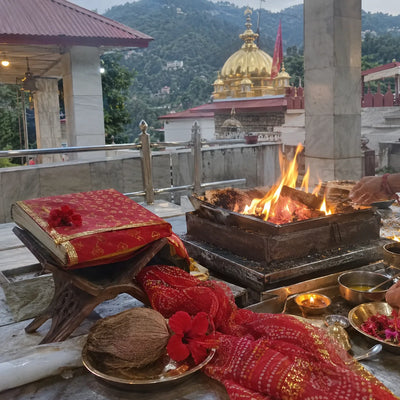 Scripture on a stand beside a havan fire with a chunri and a coconut