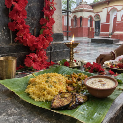 Bengali bhog of khichuri and payesh on a banana leaf with red hibiscus