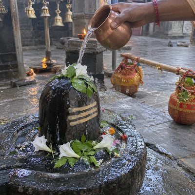 Gangajal poured over a Shivling with bilva leaves, a kanwar resting nearby