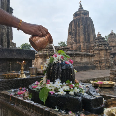 Gangajal and flowers offered on a Shivling, Kalinga-style temple spire behind