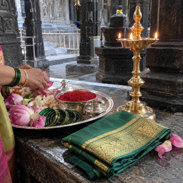 Kunku, green bangles, a silk saree and lotus flowers with a brass samai lamp