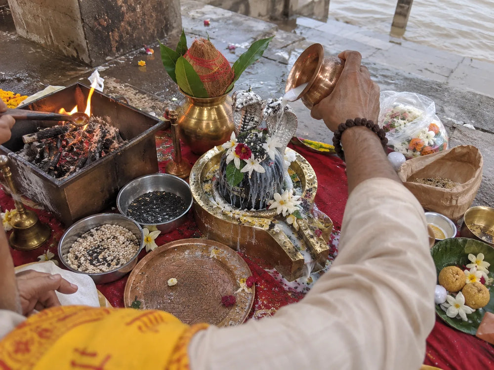 Kaal Sarp Dosh Nivaran Puja: abhishek of the silver nag-nagin pair on a Shivling beside the havan