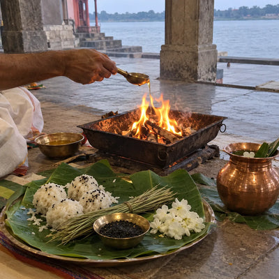 Ghee offered into a small havan fire beside rice pindas, sesame and kusha grass