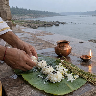 Rice pindas, sesame seeds, kusha grass and white flowers on a banana leaf by the Narmada