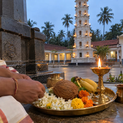 Puja plate with flowers, coconut and a lamp, Goan temple lamp tower behind