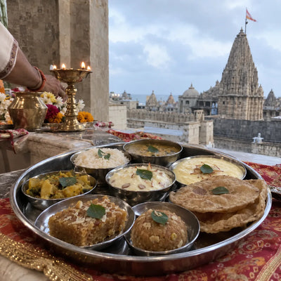 A silver rajbhog thali of Gujarati dishes with tulsi leaves