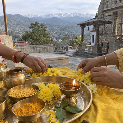 Yellow flowers, turmeric and a diya offered together on a yellow cloth