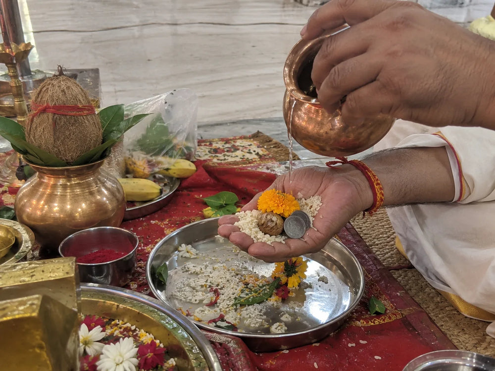 Rog Mukti Hanuman Puja: the sankalp, water poured over flowers and rice in the devotee's palm, a kalash beside