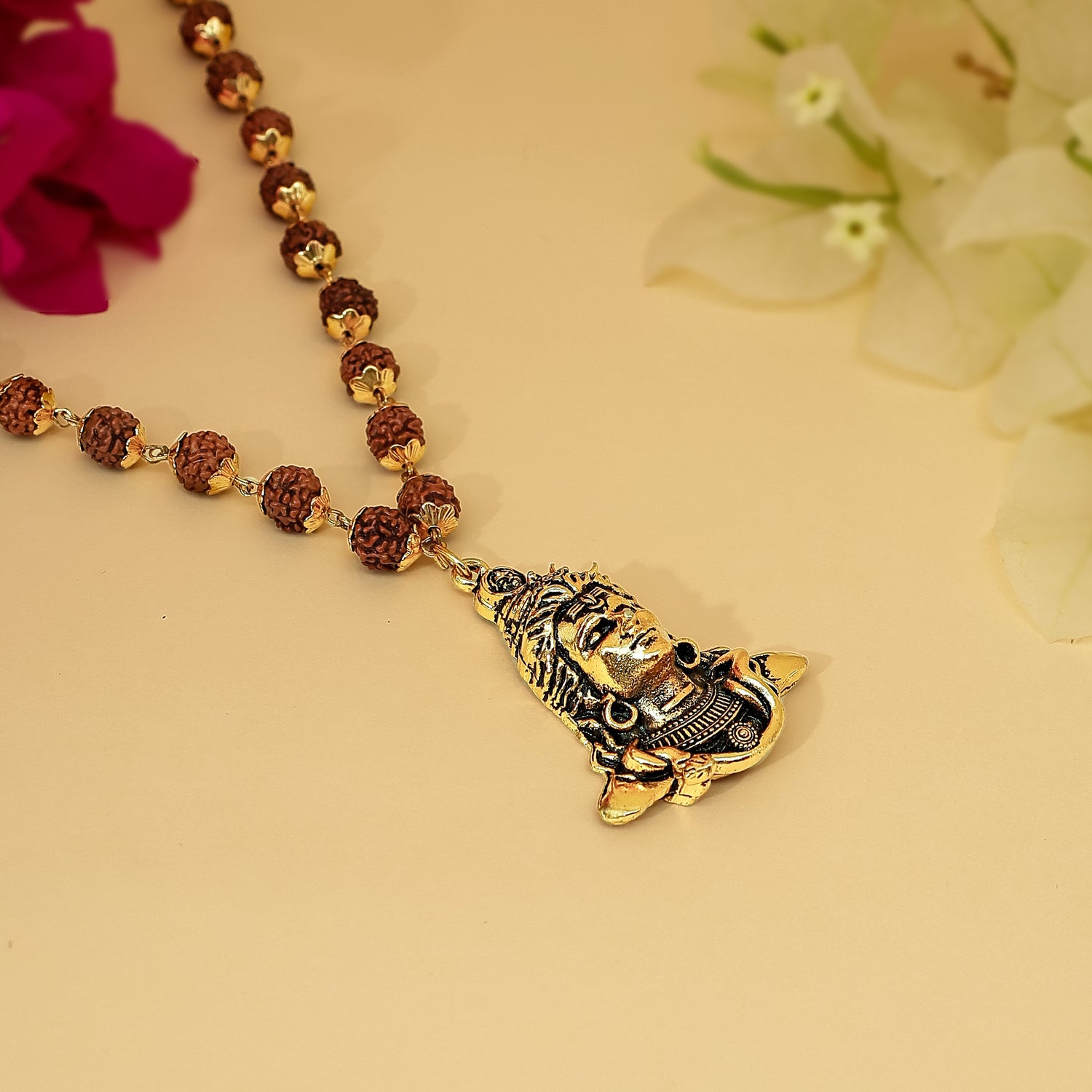 Rudraksha Necklace with gold pendant and Rudraksha beads on a beige background