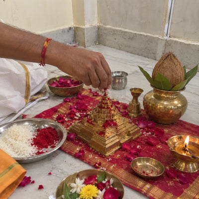 Kumkum offered on a brass Shree Yantra with rose petals and a ghee diya