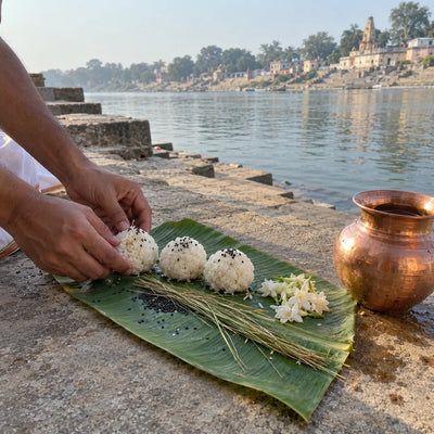 Hands placing three rice pinds on a banana leaf with black sesame, kusha grass and flowers