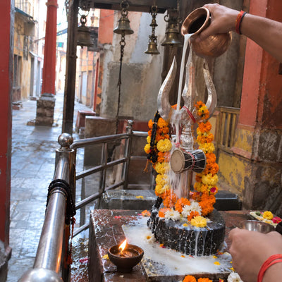 Milk abhishek of a garlanded silver trishul with a damru